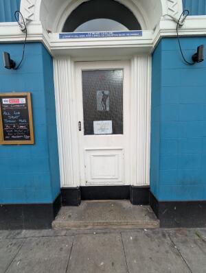 White wooden door with glass panel ahead. Push from left to open.