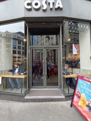 Glass doors with grey metal frame. Push handles in center to open. Step up ahead of doors.