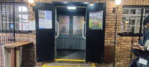 Wooden brown door ahead. Pull metal handle at center. Grab rails along both sides.