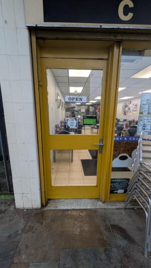 Yellow wood-framed glass door. Push from metal handle on right to open.