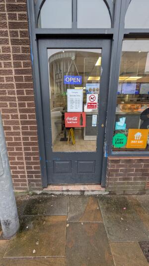 Dark grey wood-framed glass door. Push from handle on left to open.