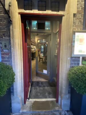 Red wooden door. Turn silver metal handle and push from right to open.