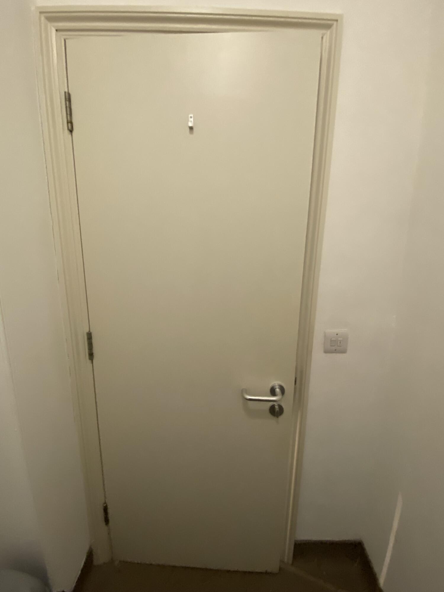 Back of door. Turn and pull silver metal handle from right to open. High hanging hook in centre. Light switch to the door right.