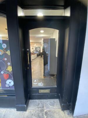 Black framed glass door. Push gold metal handle from left to open.