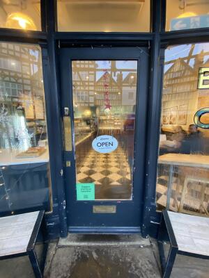 Black framed glass door. Push from left to open.