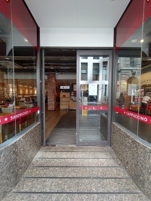 Glass doors with grey frame, silver vertical handle in middle. Push to open.