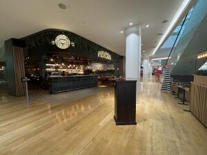 From mall pathway facing venue. Welcome desk on front right. Path on left to bar counter at back.