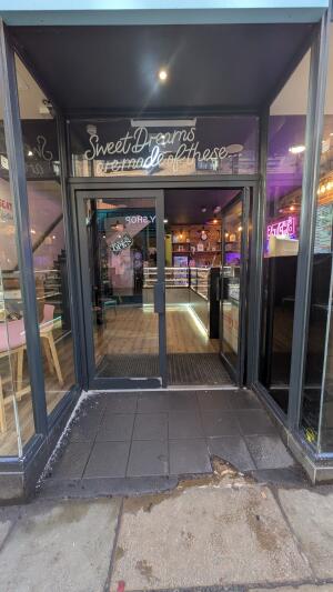 Dark metal-framed glass doors. Push from handle on left to open.