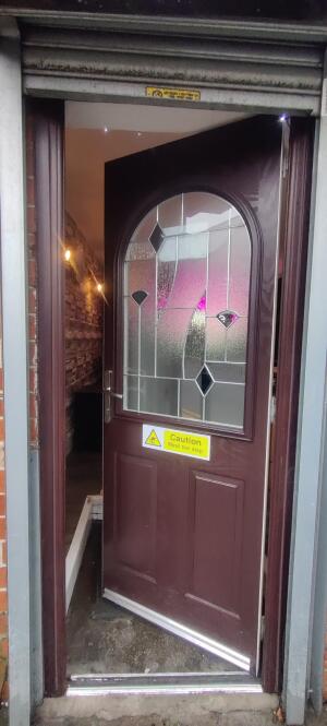 Brown wooden panelled glass door ahead. Twist push metal handle at left.