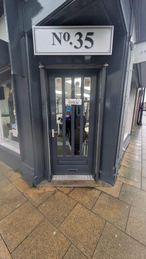 Dark grey wood-framed glass door. Push from handle on left to open.