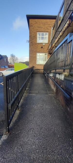 Ramp up ahead. Handrails along both sides. Landing space beyond.