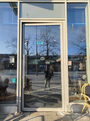 White framed glass door ahead. Push silver handle on left to open.