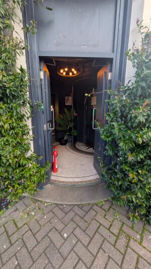 Dark grey wood-panelled double doors. Push from metal handles at centre to open.