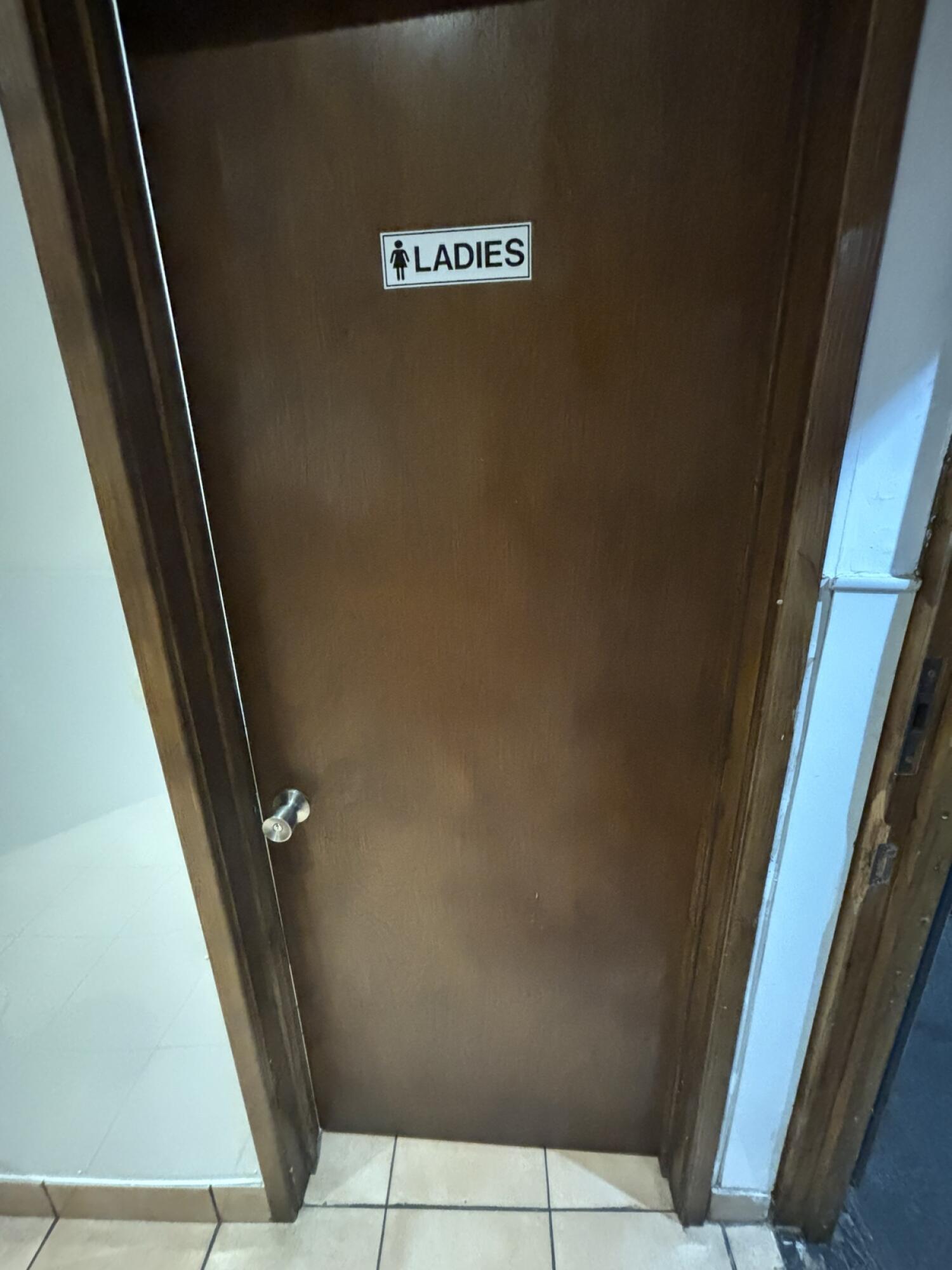From door facing right. Brown toilet door ahead. Push from left to open.