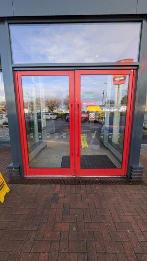 Red metal-framed glass doors. Pull from handles at centre to open.