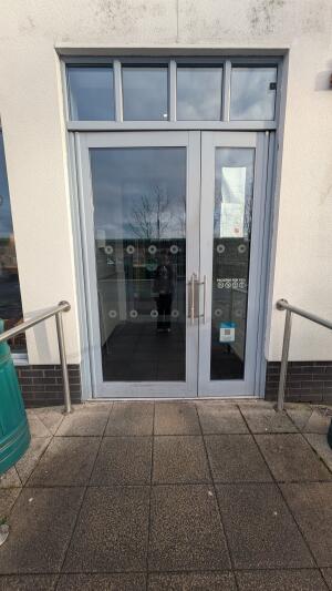 Grey metal-framed glass doors. Push from handles at centre to open.