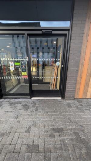 Black metal-framed glass door. Automatic door slides left to open.