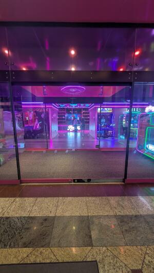 Glass doors with pink frame. Doors slide open to both sides. Doormat after door.