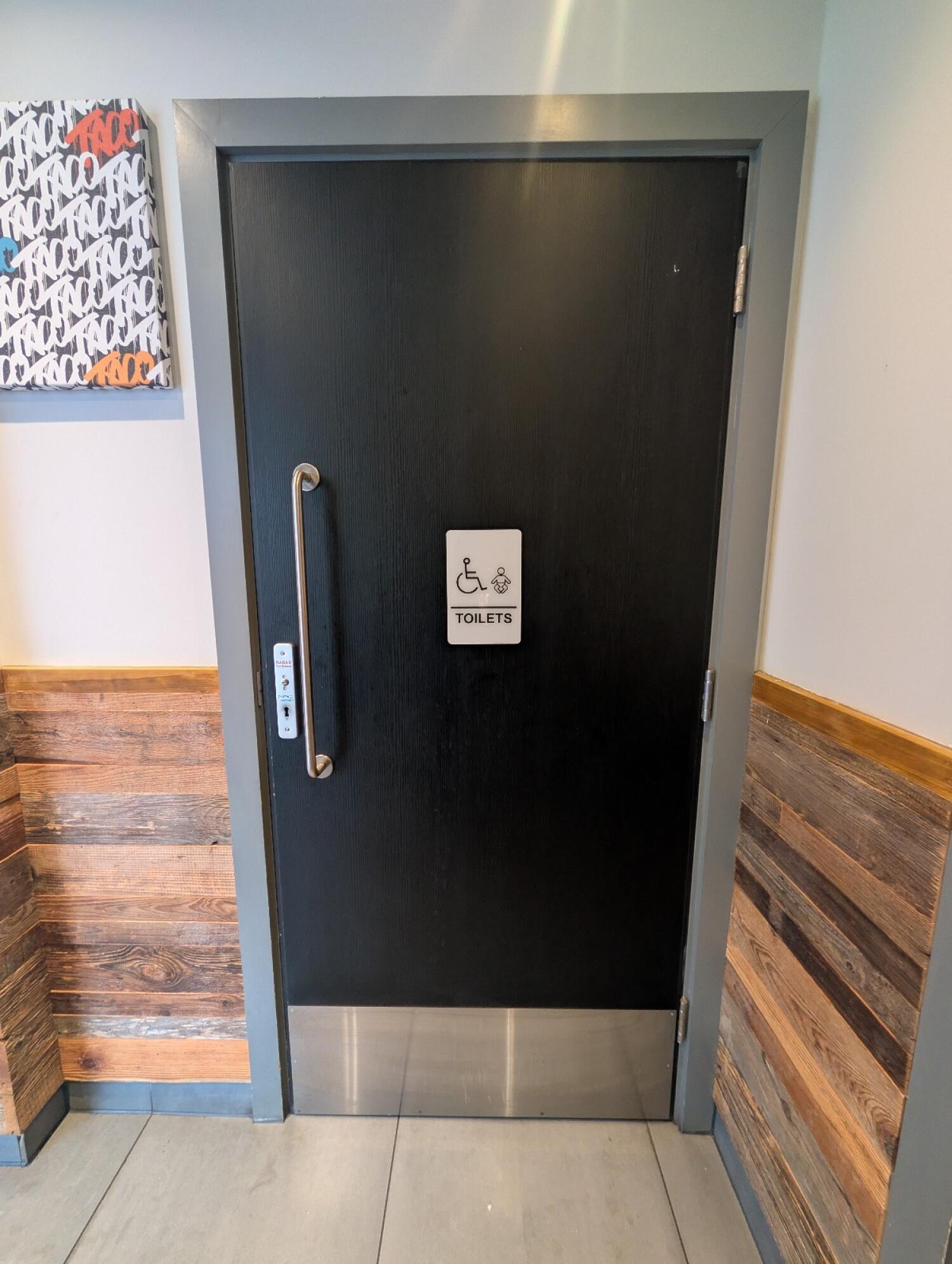 From opening facing left. Grey frame black door in front. Silver handle on left. Radar key hole on left. Pull to open.