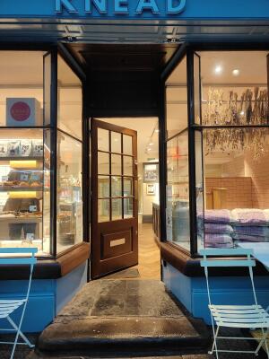 Archway ahead to venue. Brown framed door with multiple glass panels at back. Push golden bar on right to open.
