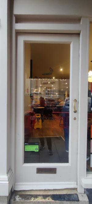 White panelled glass door ahead. Push metal handle along right.