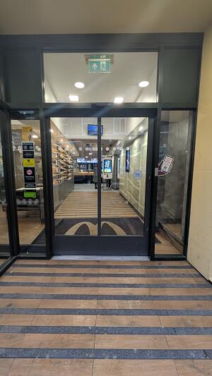 Black metal-framed automatic glass door. Door slides left to open.