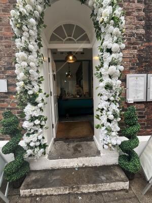 White wooden door with floral archway. Push from handle on right to open.