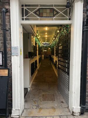 White doorframe with metal gate ahead. Push handle on left to open. Corridor ahead.