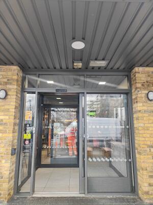 Grey framed automatic glass doors ahead. Doors slide sideways to right to open.