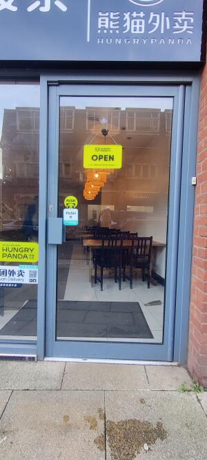 Grey metal framed glass door ahead. Push metal handle along left to open.