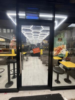 Black metal-framed glass door. Push from metal handle on left to open.