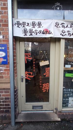 Beige framed glass door to venue. Push handle on left to open.