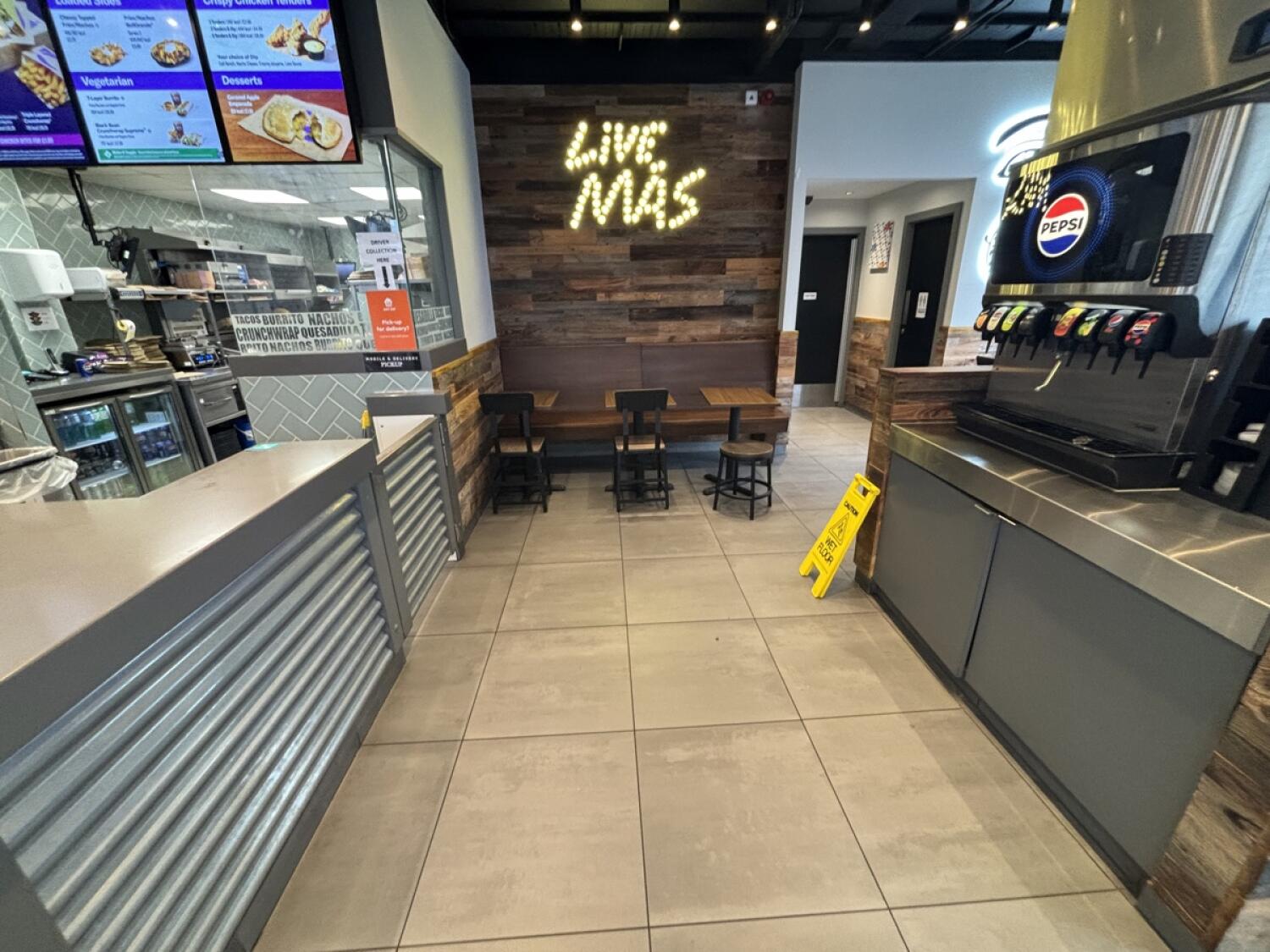 From opening facing left. Half booths and chairs at back. Path ahead to toilet at back right.
