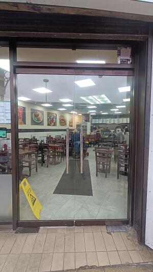 Brown framed glass door to venue. Push handle in centre to open.