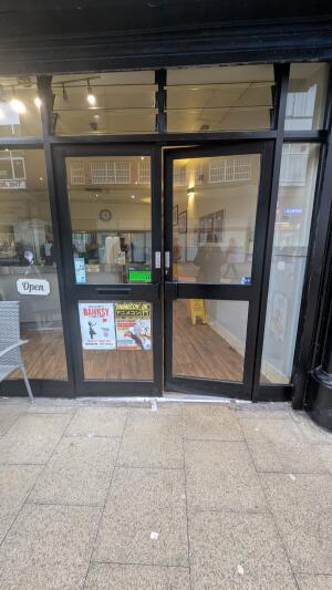 Black metal-framed glass door. Push from handle in centre to open.