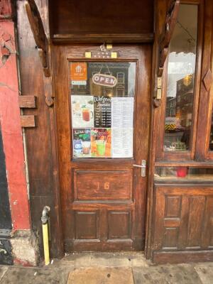 Brown wooden door in front with glass panel. Silver handle on right. Push to open.