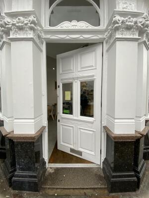 White wooden door with glass panelling. Push silver metal handle from left to open.