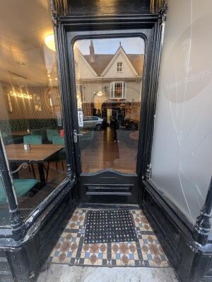 Opening in front. Black frame glass door at back. Silver handle on left. Pull to open.