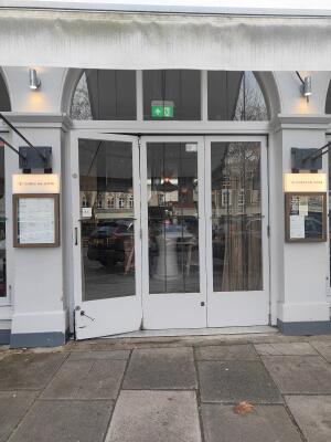 White framed glass door ahead. Pull bronze handle in left to open.