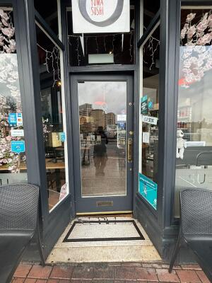 Grey framed glass door ahead. Push bronze bar on right to open.