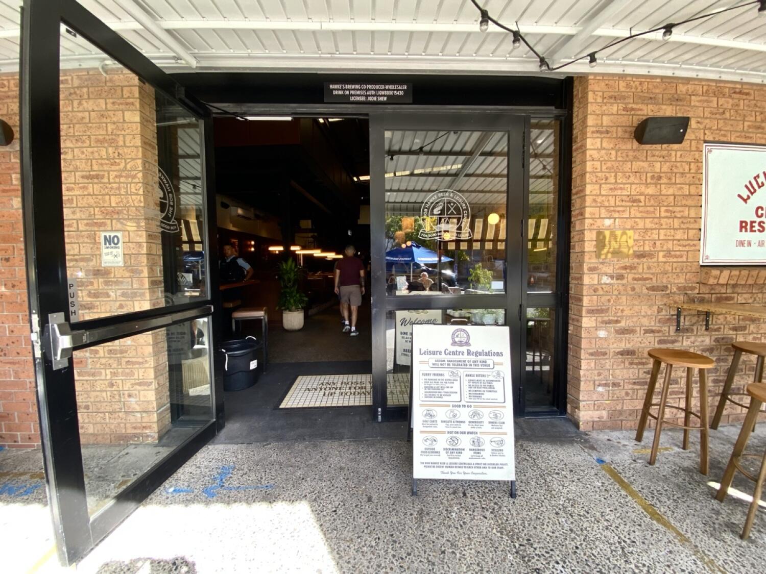From opening facing straight. Black metal-framed glass doors ahead. Pull from handles in centre to open.