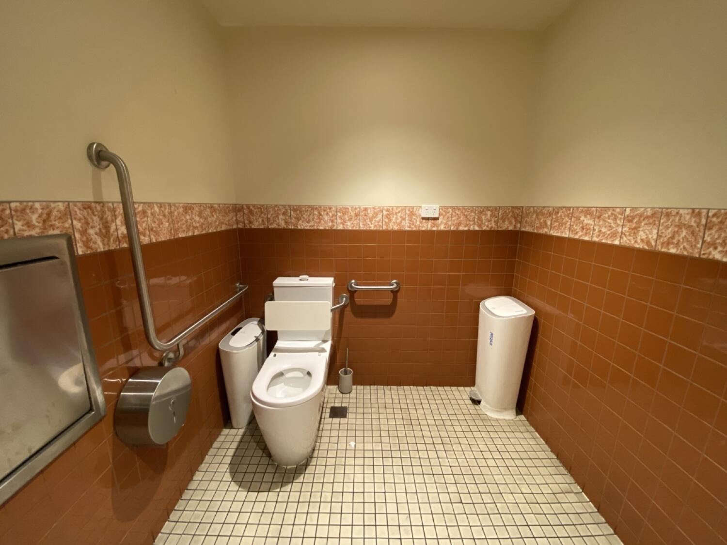 From sink facing right. Toilet at back left wall. Bin to its left. Second bin on right wall.