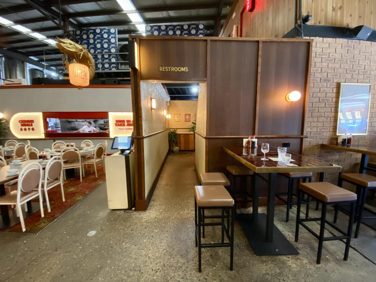 From after welcome desk facing right. Opening at back to bathroom. High table with stools on right.