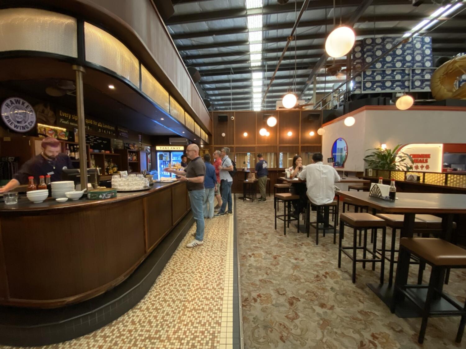 From start of counter facing right. Bar and food counter along left. Path ahead to more high tables and stools along right.