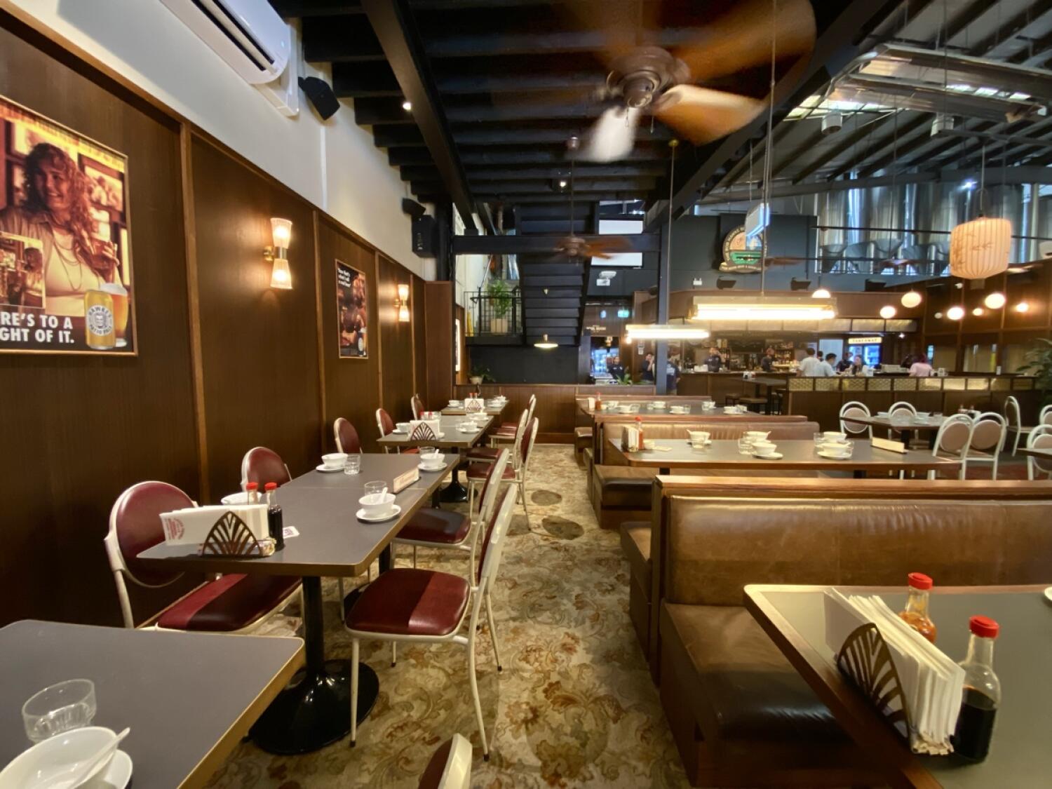 From end of path facing right. Tables and chairs along left wall. Booth seating along right.