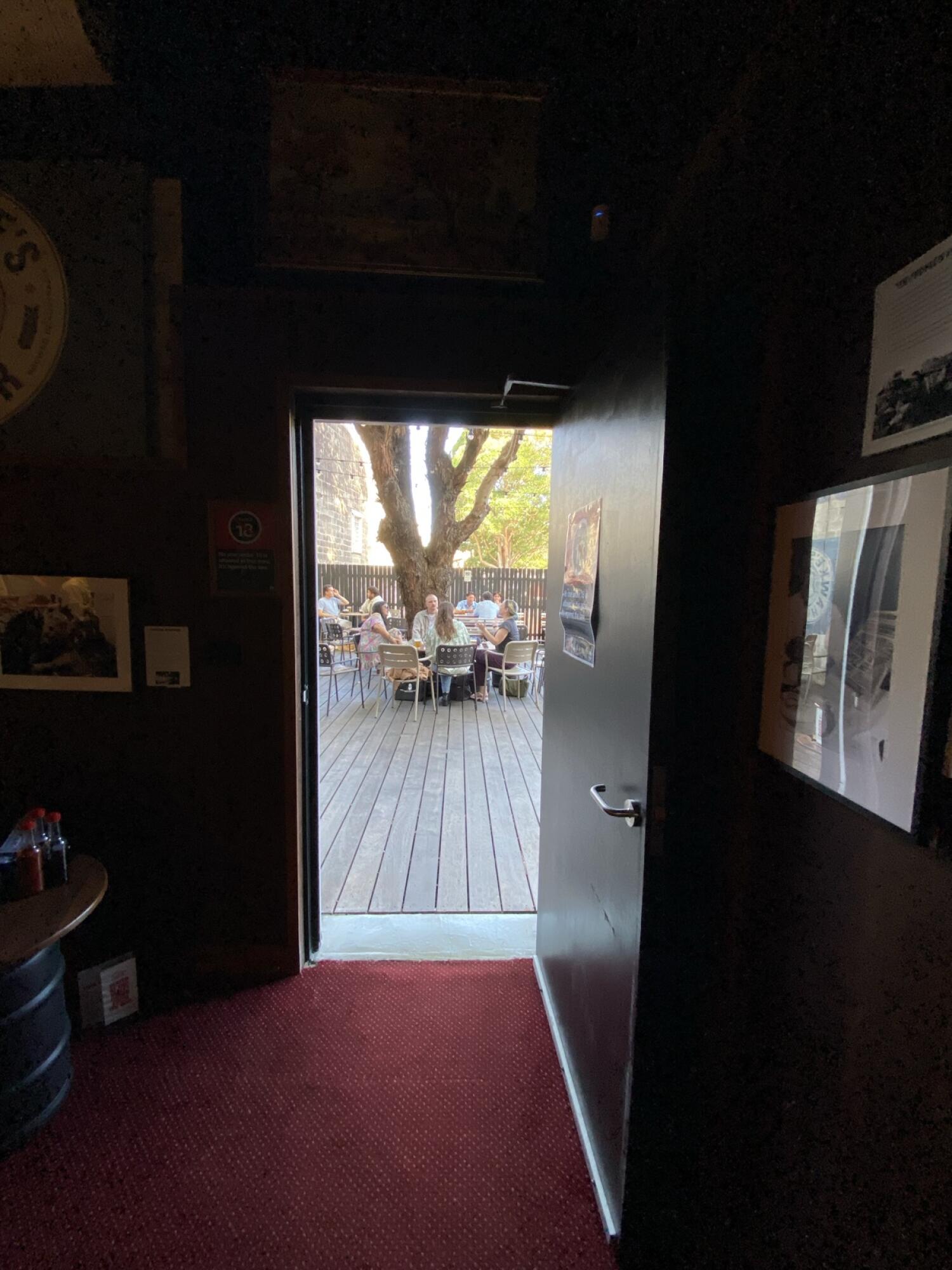 From back right of back space facing straight. Dark wooden door ahead. Pull from metal handle on left to open.