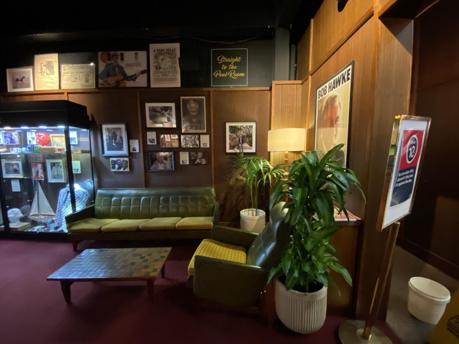 From archway facing right. Couch and armchair with low table ahead. Planters on right.