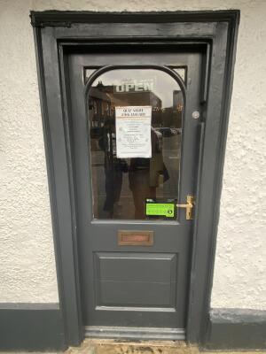 Dark grey wood-framed glass door. Pull from gold metal handle on right to open.