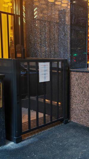Black metal wheelchair lift at entrance. Small bump at foot of lift.
