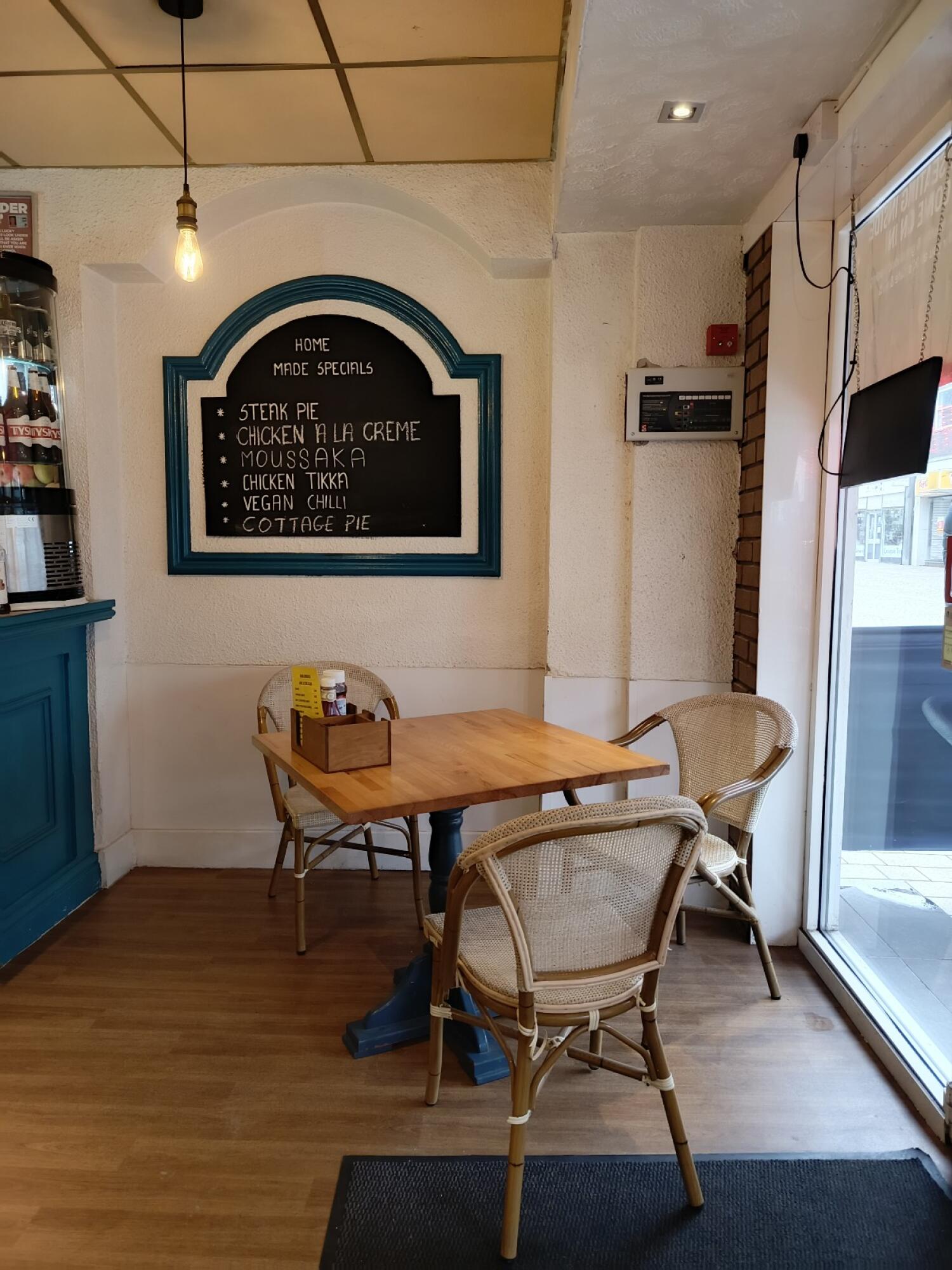 From entrance facing right. Counter on right. Table and chairs at centre.